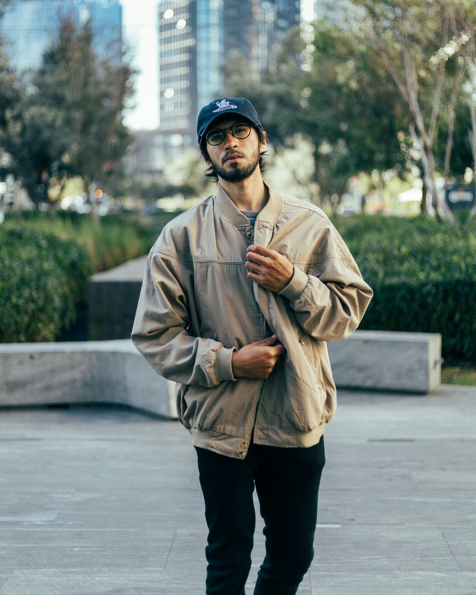a man standing on a sidewalk wearing a hat and jacket